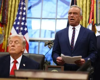 a man speaks next to a man seated at a desk