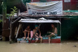 Men drink and socialise at an inundated village, amid southwest monsoon rains in Bagong Silangan, Quezon City, Philippines. Photo: Reuters
