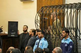 Ateb Najib stands inside a cage wearing a striped uniform as he is sentenced in a courtroom in Damascus, Syria.