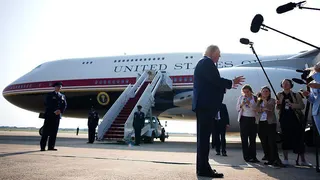 Trump stands in front of Qatari-gifted Air Force One and speaks to reporters who are holding boom microphones