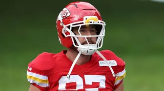 Travis kelce wearing a red jersey and a red and white football helmet.