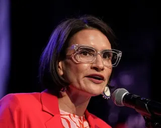Woman in red blazer speaks into mic