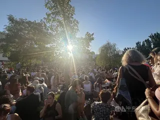 許多巴黎人與遊客12日晚間聚集在安德瑞・雪鐵龍公園觀賞日偏食。部分人群坐在草地上野餐，與親友聊天。中央社實習記者洪嘉琪巴黎攝　115年8月13日