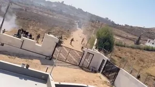 men and tear gas are seen outside ythe yard of a family home in the west bank