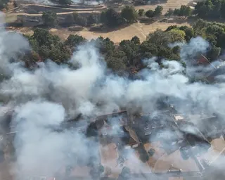 An aerial view of smoke from the grassfire engulfing homes and woodland