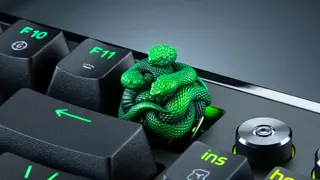 A Razer artisan keycap, made up of three green resin-cast snakes, attached to a gaming keyboard