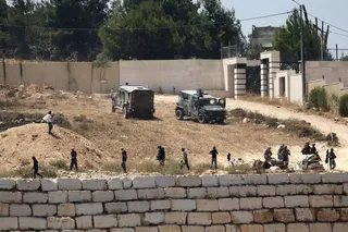 Israeli soldiers stand guard next to settlers in front of Palestinian homes that they have blockaded in the village of Qusra, south of Nablus, in the occupied West Bank, Wednesday, Aug. 12, 2026. (AP Photo/Nidal Eshtayeh)