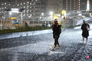 8月13日，暴雨席卷日本千叶县，人们走在雨水淹没的道路上缓缓前行。 （法新社）