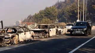 A firefighter truck is parked next to burnt cars on a road after a wildfire near the town Omis, some 30 kilometres south of Split.