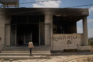 A youth enters a mosque that was burned during an attack by Israeli settlers early in the morning in the West Bank village of Qusra, Sunday, July 26, 2026, as on its wall a Hebrew graffiti reads "Revenge Benayahu", referring to an Israeli settler killed during clashes with Palestinians in the village of Tell, last Friday. (AP Photo/Leo Correa)