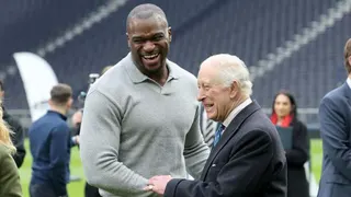 Efe Obada meets King Charles at an event to showcase the charitable work of Tottenham Hotspur and the NFL in February 2025
