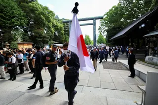 A person carries a Japanese flag as people visit to pay tribute to the war dead at Yasukuni Shrine in Tokyo on Saturday on the 81st anniversary of Japan’s surrender in World War II. Photo: Reuters