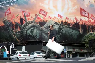 An Iranian woman walks next to an anti-US sign at Enghelab square in central Tehran, Iran on Thursday. Photo: EPA