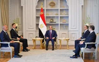 men in suits sit in room during meeting
