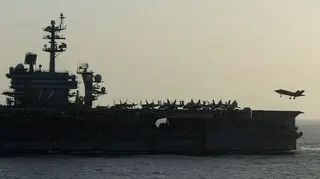 美國海軍亞伯拉罕·林肯號航空母艦（USS Abraham Lincoln）於2026年4月16日在阿拉伯海執行與霍爾木茲海峽相關的美國封鎖行動。照片拍攝航空母艦側面景觀，一架小型噴射戰鬥機正要降落於甲板上。