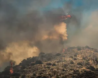 A firefighting helicopter drops water during a wildfire in the island of Salamina, near Athens.