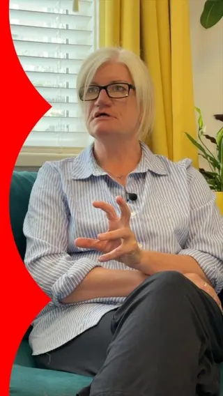 A woman wearing a striped shirt is sat on a sofa