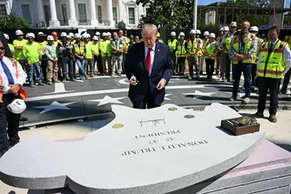 美国总统特朗普当地时间周三在白宫南草坪的直升机停机坪施工现场一块石头上签名。（图取自法新社）