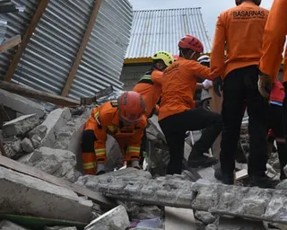 Rescue teams search collapsed buildings for possible victims trapped under the rubble following a powerful earthquake in Indonesia.