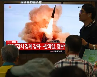 People look at a screen showing a missile being fired.