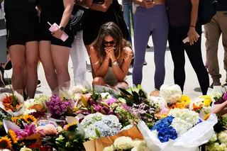 A woman kneels and prays at a flower memorial to shooting victims outside the Bondi Pavilion at Sydney’s Bondi Beach, on December 15 last year. Photo: AP