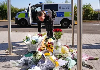 A police officer leaves flowers at the Cleveland Police HQ Memorial Garden in Middlesbrough on Monday, after two officers were killed when a car pursued by police crashed while driving the wrong way on a major road. Photo: dpa