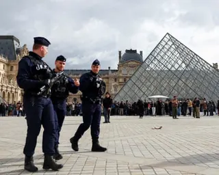 Three armed police outside the Louvre pyramid
