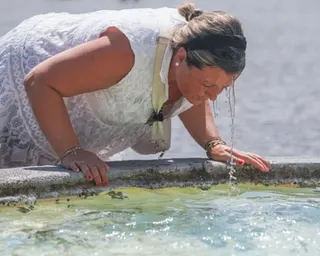 Water runs off a woman's face after she dips her head in a fountain pool