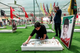 A boy cleans one of the graves of people and children killed during the strike on the Shajareh Tayebeh primary school at a cemetery in Minab in Iran痴 Hormozgan province on August 10, 2026. Six months on, a team of AFP journalists obtained rare access to the school which has remained largely in ruins, its collapsed walls and twisted steel now surrounded by portraits of the children killed as Iranian flags flutter above the rubble. Iran says the attack on the school involved two separate US Tomaha
