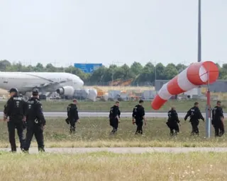 A group of police officers walk across an expanse of grass between runways at Leipzig airport