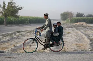 Afghan children ride a bicycle at a village in the Dand district of Afghanistan's Kandahar province on August 25, 2026. — AFP pic