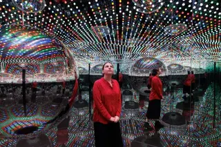Getty Images A visitor standing in one of Kusama's Infinity Rooms, seen reflected several times in mirrors surrounded by lights