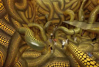 AFP via Getty Images A series of intertwining tentacles in black and yellow polka dot run through a large room with mirrors in the centre, with visitors walking through it, in Basel in 2025.