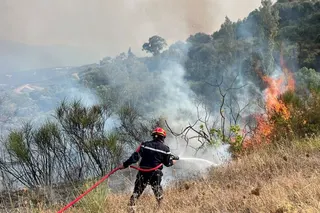 A firefighter works to extinguish a fire, as a wildfire due to rising temperature sweeps through several villages in the mountainous Bejaia province, in Taourirt Ighil, Algeria, August 19, 2025.
