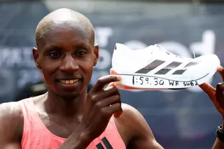 Kenya's Sabastian Sawe celebrates with a shoe after winning the men's elite race.