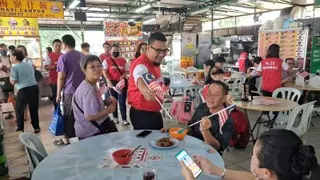 李凯业在小食中心派发国旗，获得民众踊跃索取。