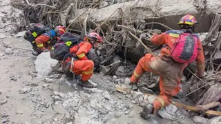 周六在中国西藏自治区日喀则市吉隆县吉隆口岸泥石流灾害现场参与搜救的救援人员，俯身检查碎石、瓦砾、钢筋等垃圾交织的废墟。（图取自新华社）