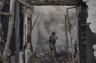 A firefighter sprays water inside a smoke-filled building damaged by a Russian strike near Kyiv