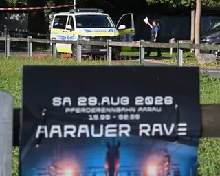 Police officers work in the background; in the foreground there is a poster advertising the rave where the shooting took place