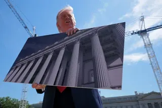 Trump holds up a rendering of ornate classical columns while speaking outdoors