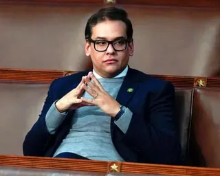 a man sits with fingertips pressed together in the House chamber