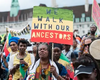 A protester in centre of picture holds a placard reading 'We walk with our ancestors'