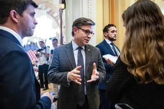 a man in a suit speaks to people holding phones in his direction