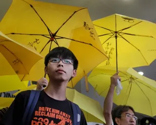 Pro-democracy activist Joshua Wong stands under yellow protest umbrellas outside a courthouse