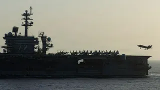 Side view of USS Abraham Lincoln as a small jet lands on it