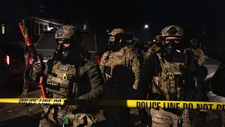 US immigration officers stand behind a yellow police line in Minnesota at night after protesters clashed with ICE agents in north Minneapolis in January 2026.