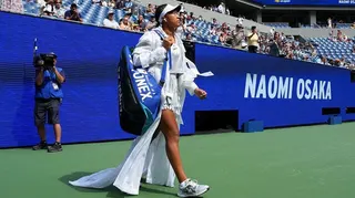 Naomi Osaka walks out on to court wearing a white dress