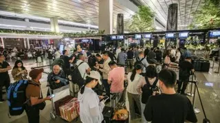 周日，大批滞留旅客聚集在印尼丹格朗的苏加诺-哈达国际机场航站楼等待航班最新消息。（图取自法新社）
